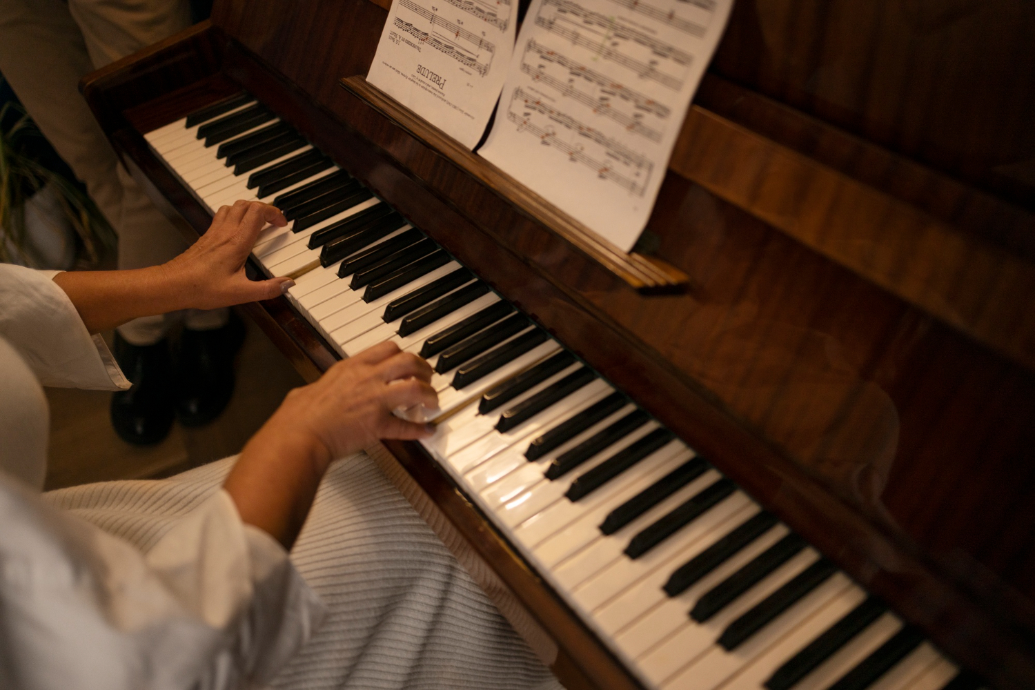 Akustik piyanoda nota sayfasını takip ederek çalan bir yetişkinin ellerinin yakın plan görüntüsü; Piyano Akademi’nin birebir piyano eğitimini yansıtan detaylı sahne.