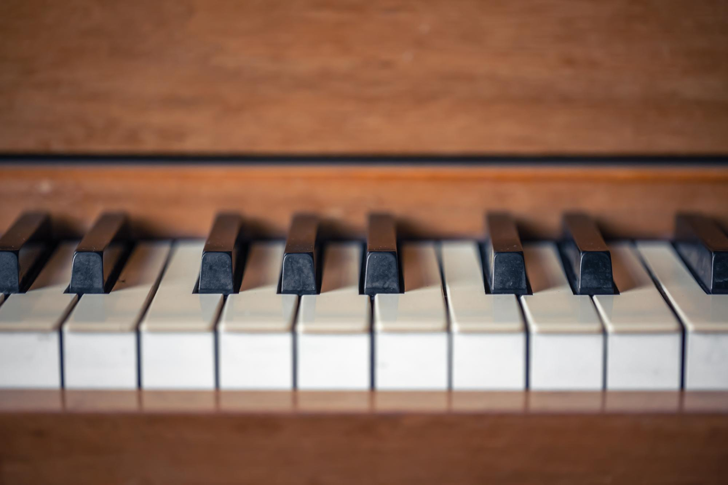 Ahşap bir akustik piyanonun siyah ve beyaz tuşlarının yakın plan çekimi; Piyano Akademi’nin enstrüman tanıtımı ve piyano eğitimi içeriklerini destekleyen detay görüntü.