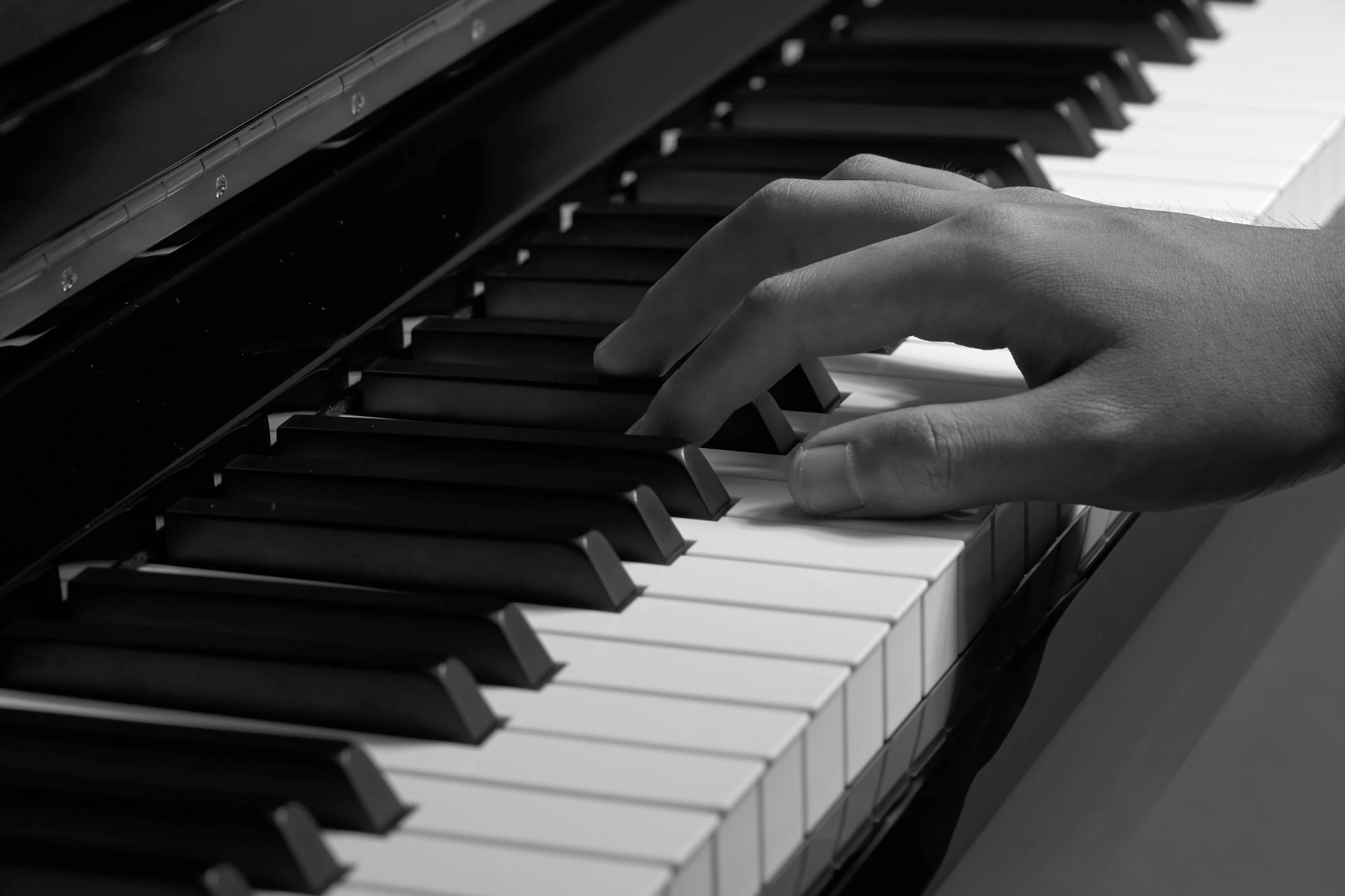 Piyano tuşlarında çalan elin siyah beyaz yakın çekimi – Piyano kursu teknik çalışması.